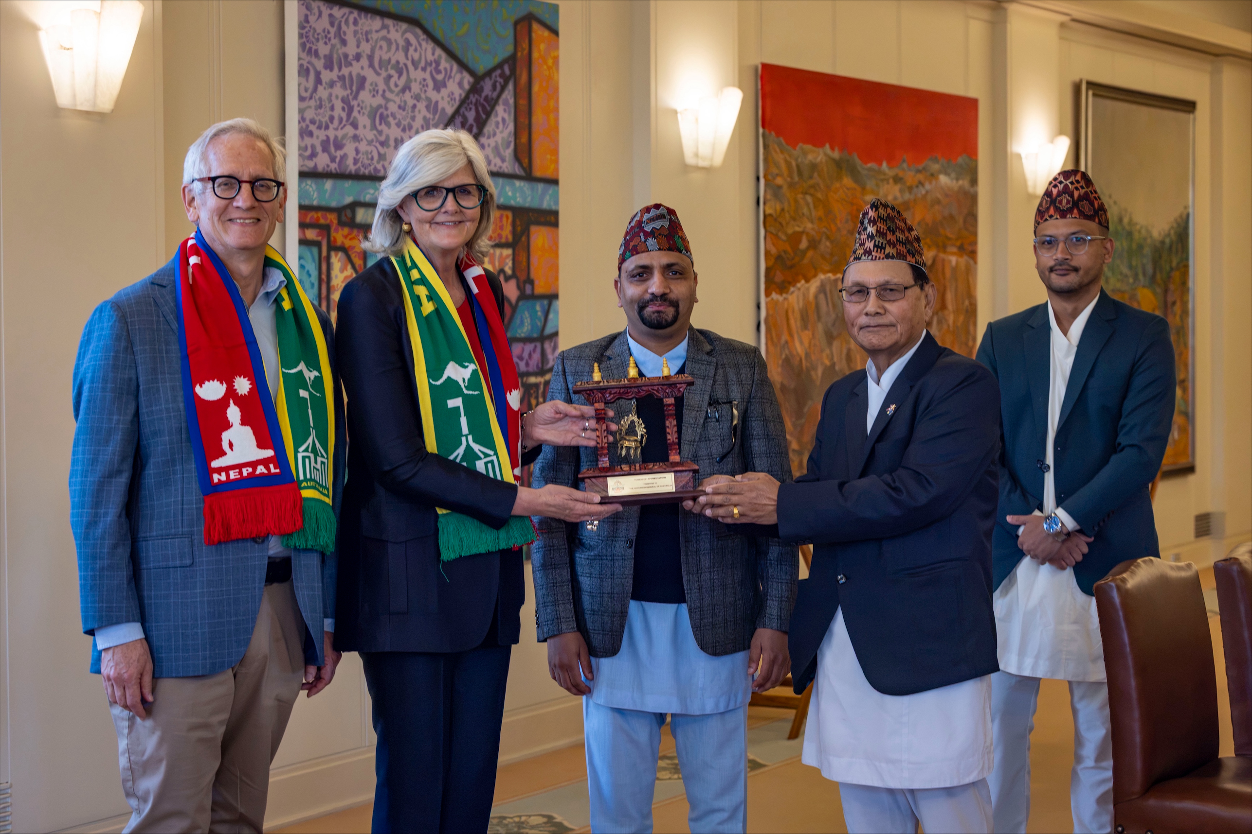 The Governor-General and Mr Beckett posing for a photo with members from the Australia Nepal Friendship Society, holding a token of appreciation.