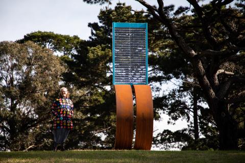 A woman stands next to a sculpture 