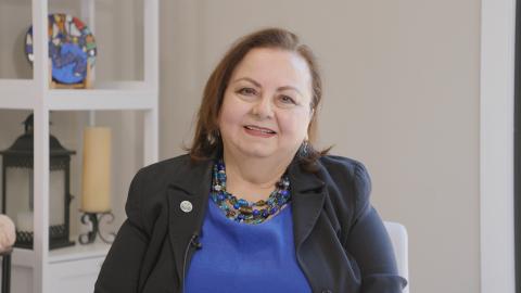 A portrait of a woman wearing a blue shirt and black jacket
