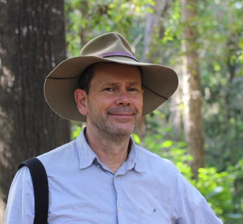 Dr Barry Traill AM smiling at camera, wearing bush hat