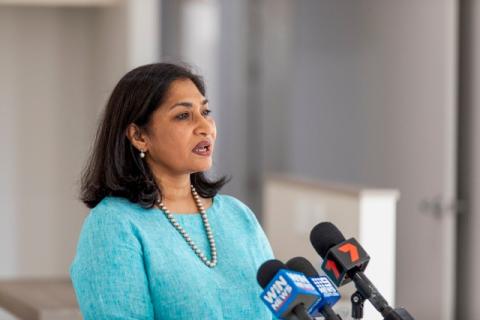 Dushyanthi Thangiah OAM speaking with microphones, wearing turquoise top