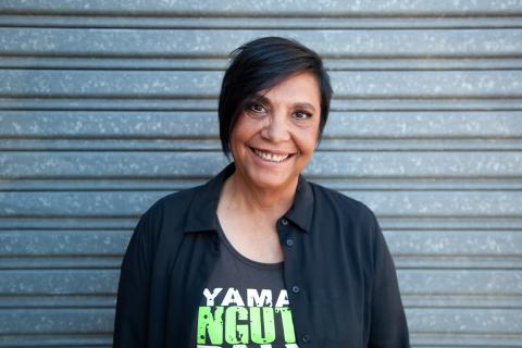 Dr Shellie Morris AO smiling at camera, wearing t shirt with green writing